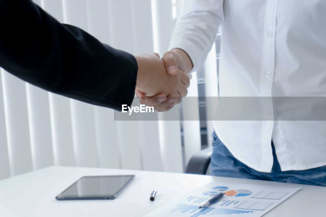 Midsection of businessman and colleague shaking hands 