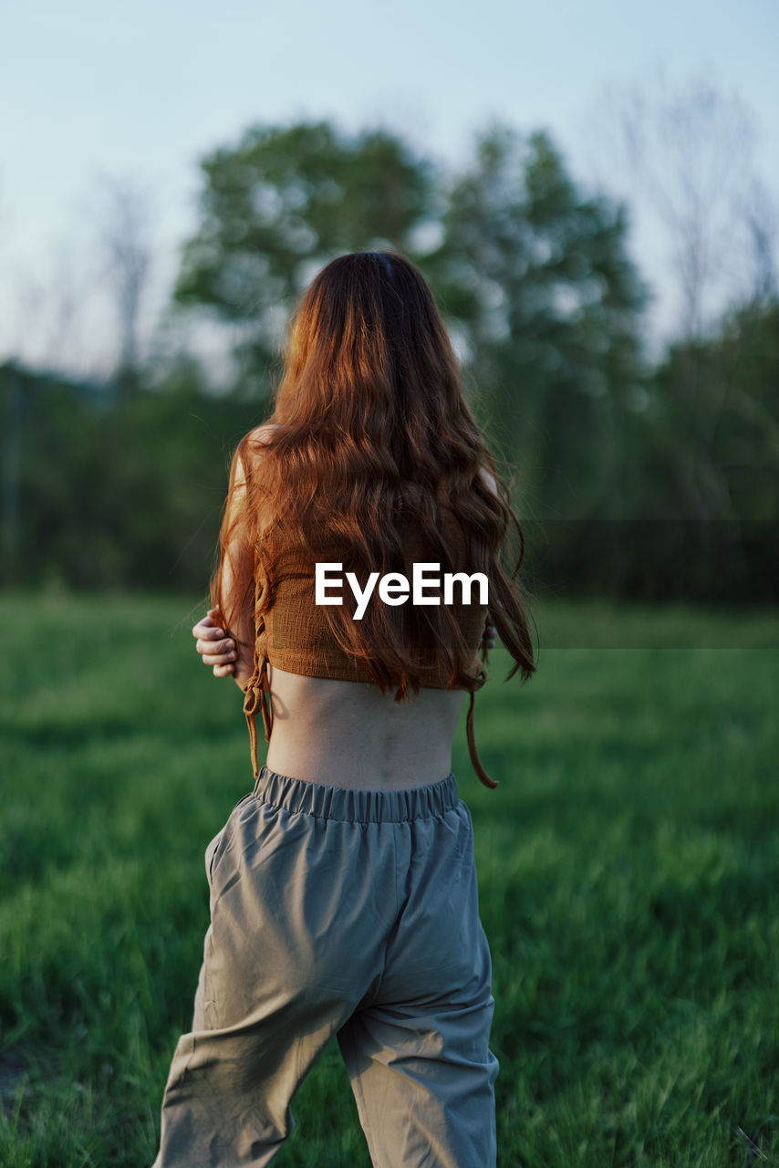 rear view of woman walking on field