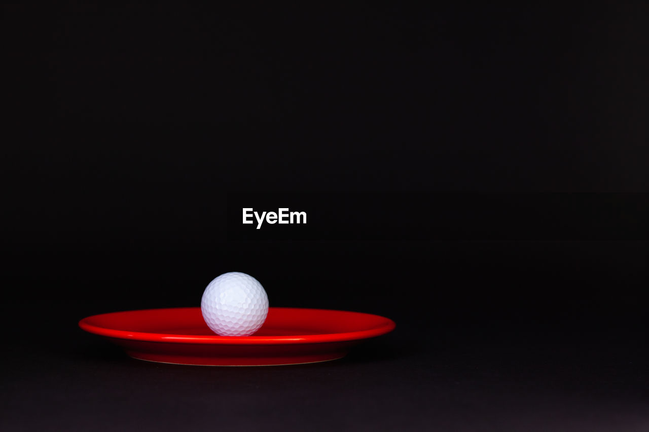 Close-up of golf ball in plate against black background