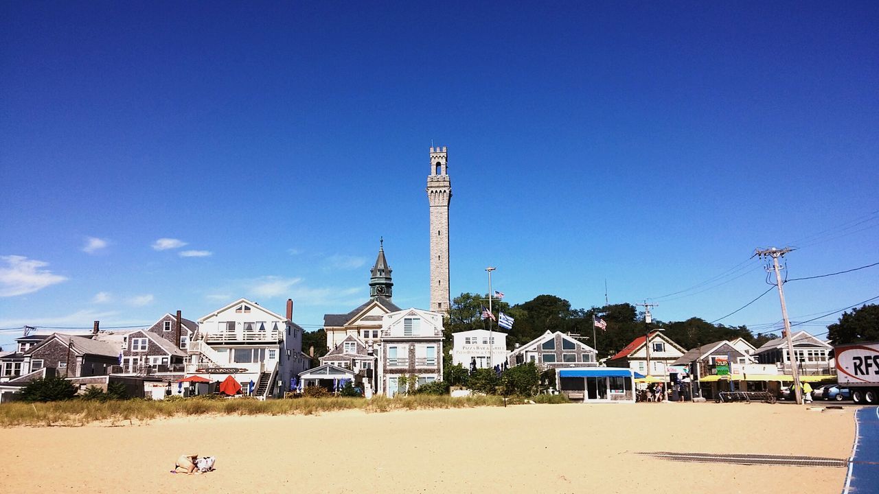 Houses at lookout tower at beach against blue sky