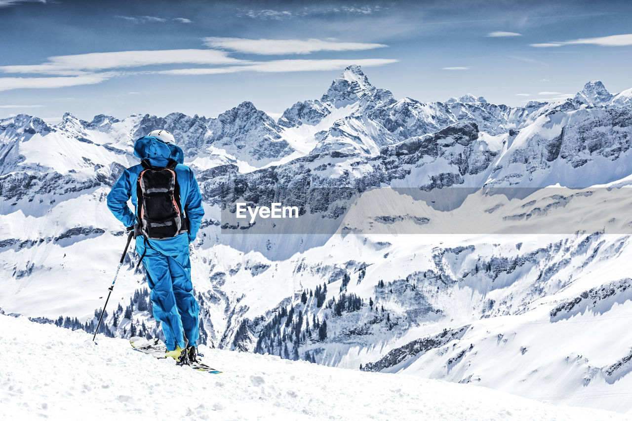 Man standing on snow covered landscape against sky