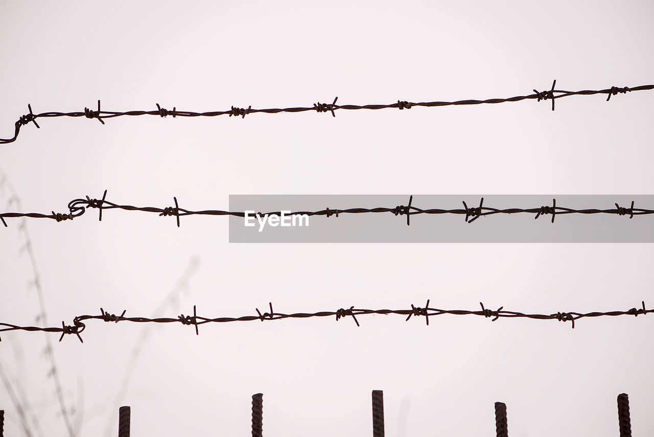 Low angle view of rusty barbed wire fence during foggy weather