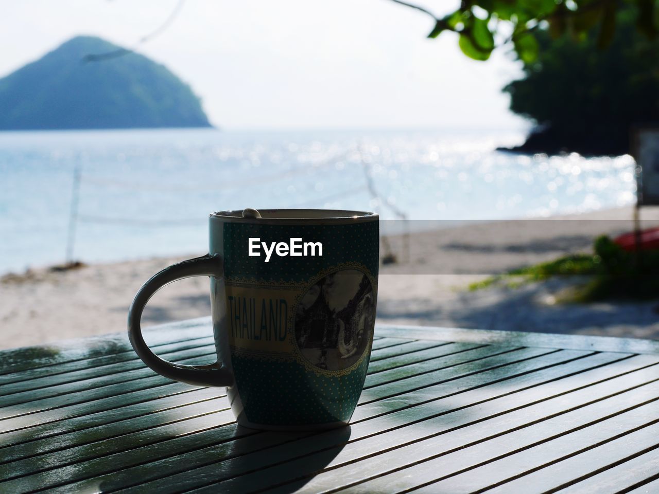 CLOSE-UP OF COFFEE CUP ON TABLE AGAINST BLURRED BACKGROUND