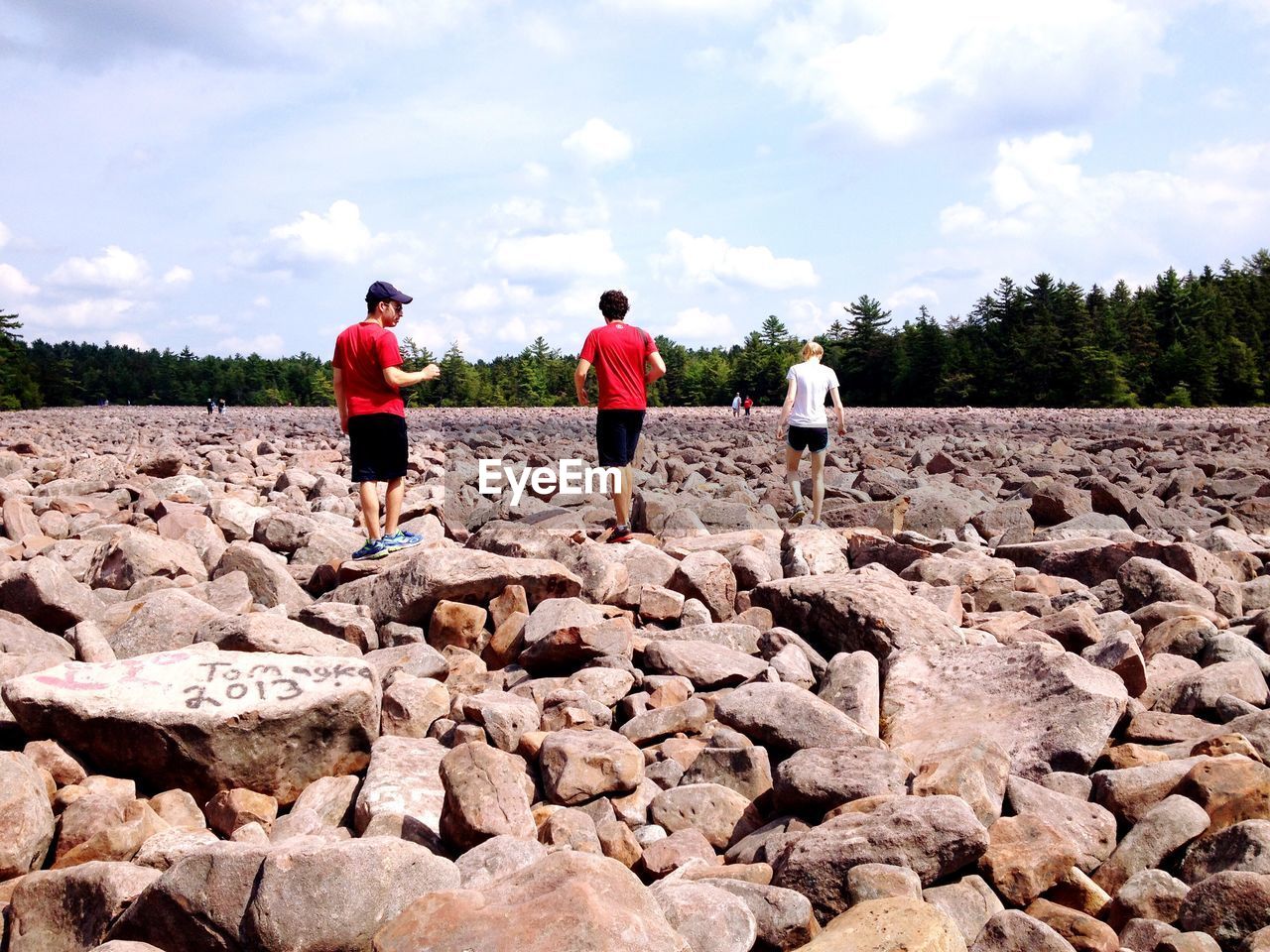 Rear view of friends walking on rocks against sky