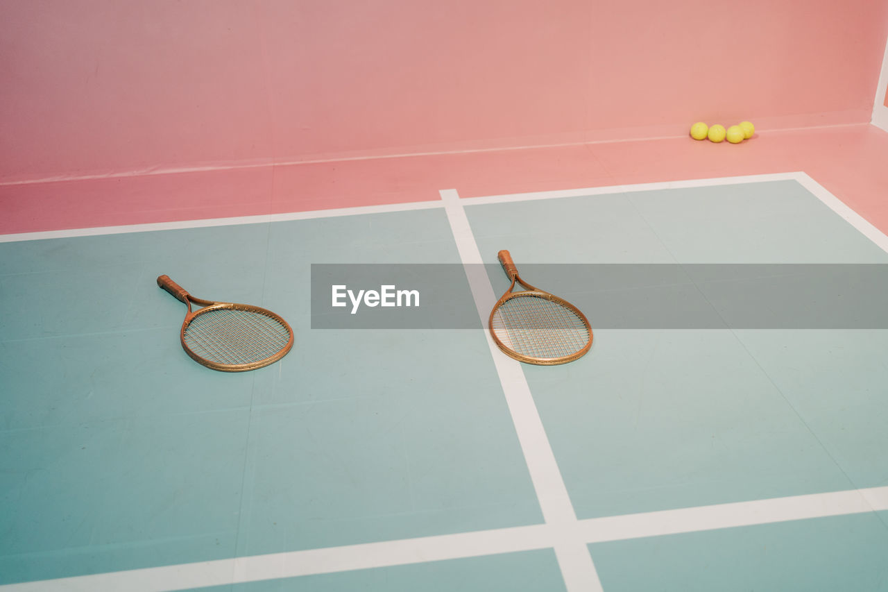 Creative design of tennis rackets against small balls on sports ground with marking lines