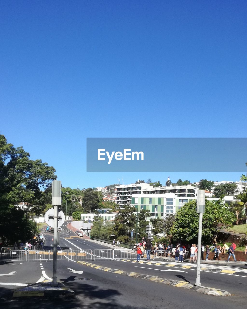 ROAD BY BUILDINGS AGAINST BLUE SKY