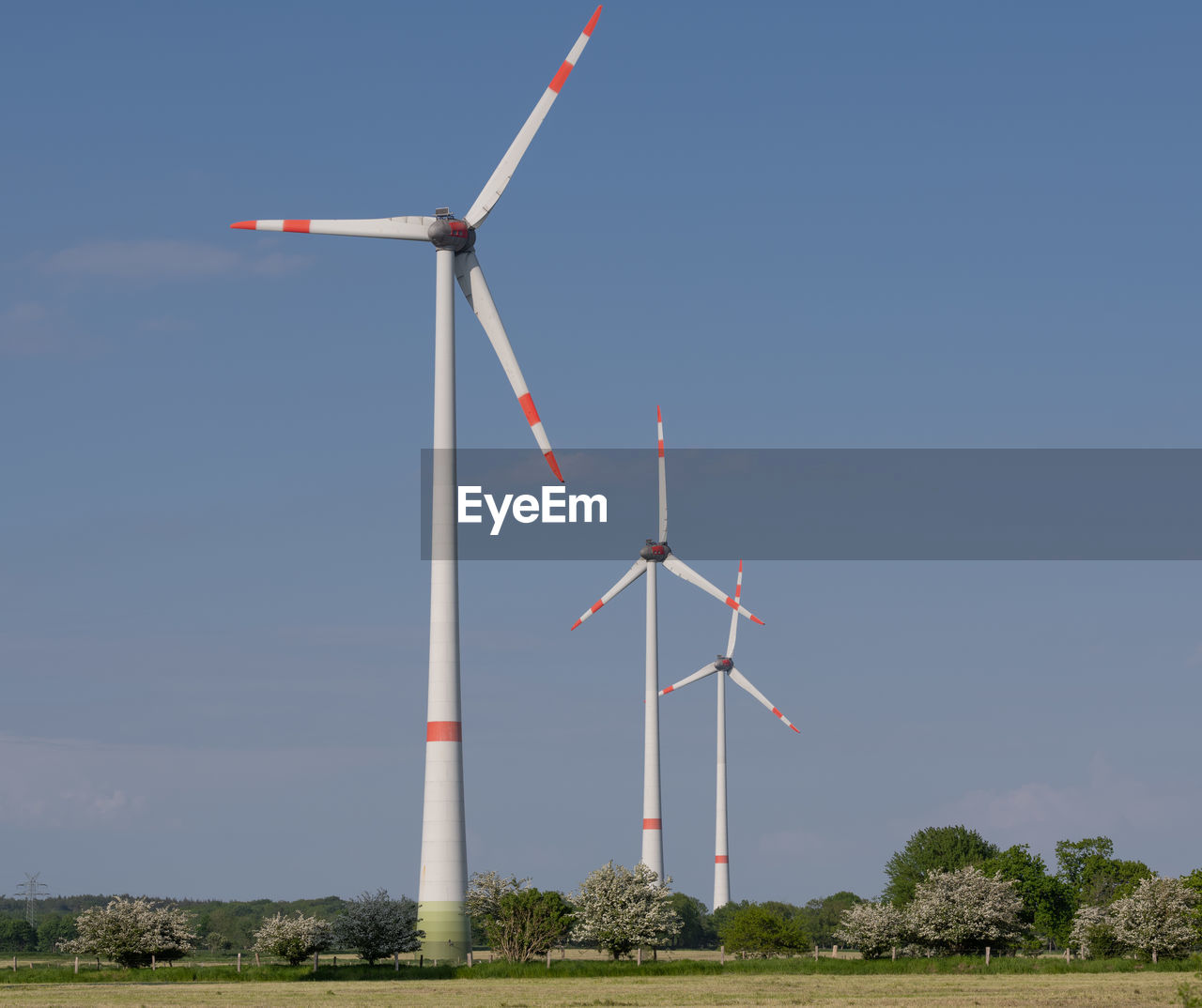 LOW ANGLE VIEW OF WIND TURBINES ON FIELD AGAINST CLEAR SKY