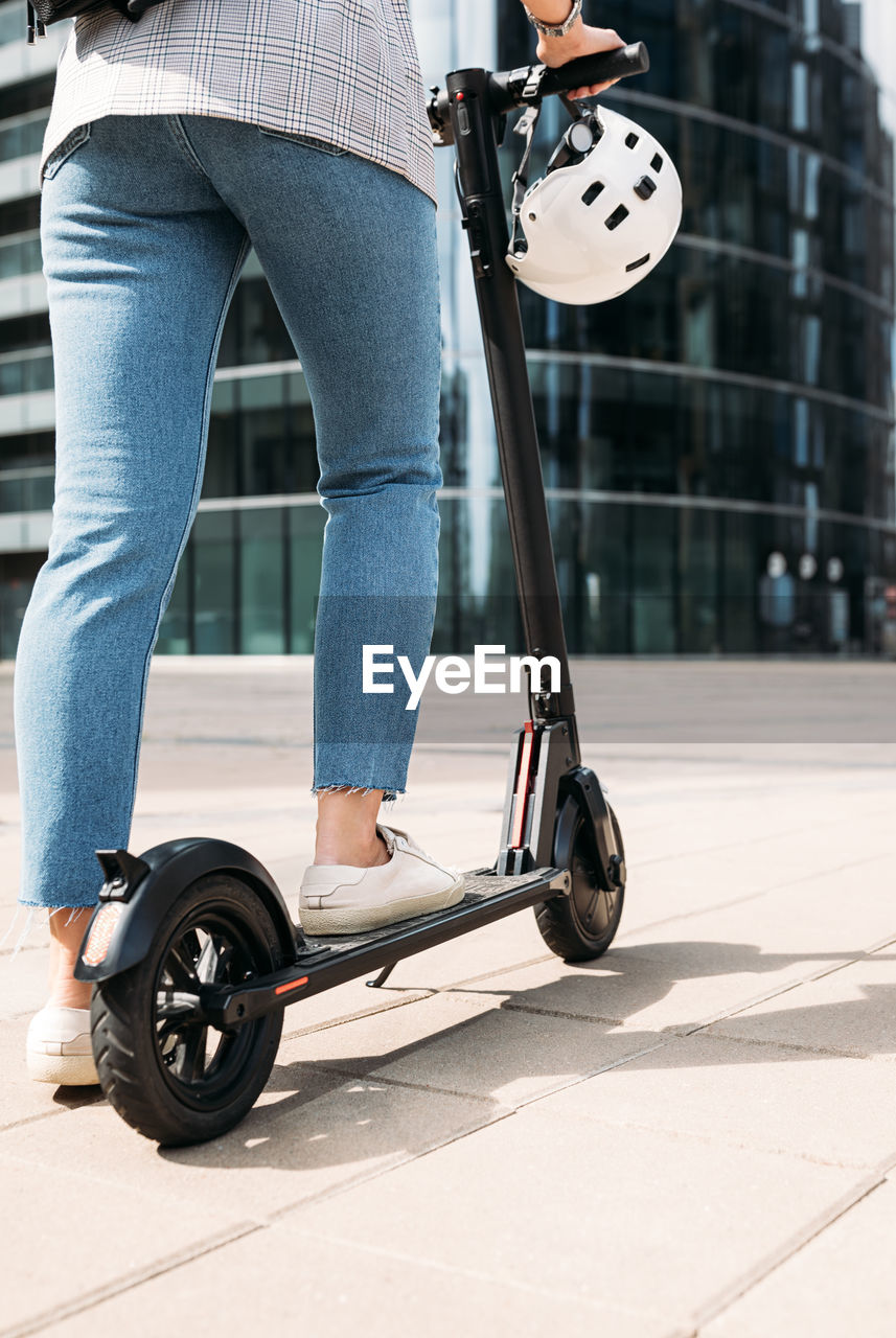 Cropped shot of unrecognizable businesswoman driving electric scooter in the city	