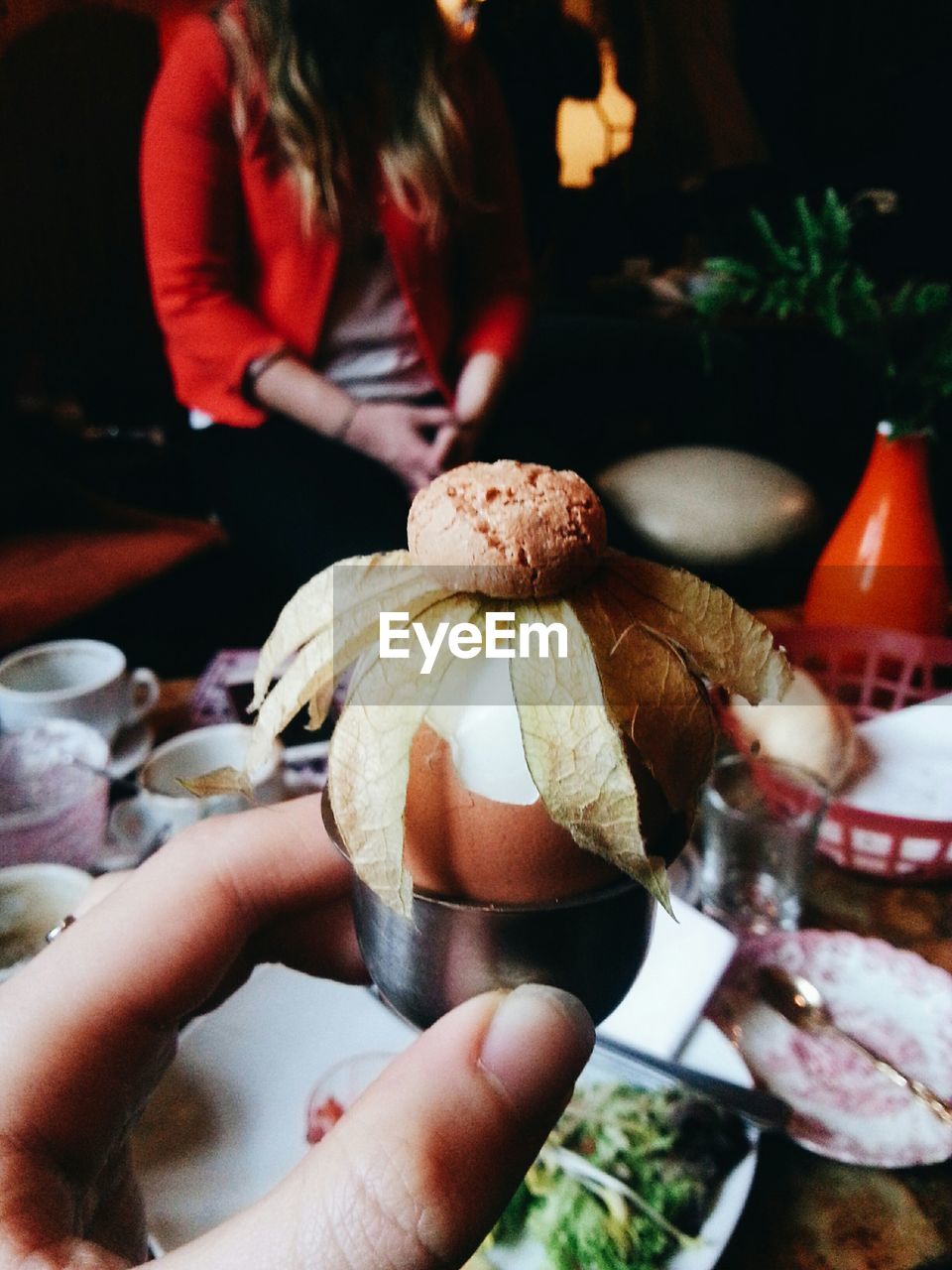 Cropped image of woman holding egg and cookie in restaurant