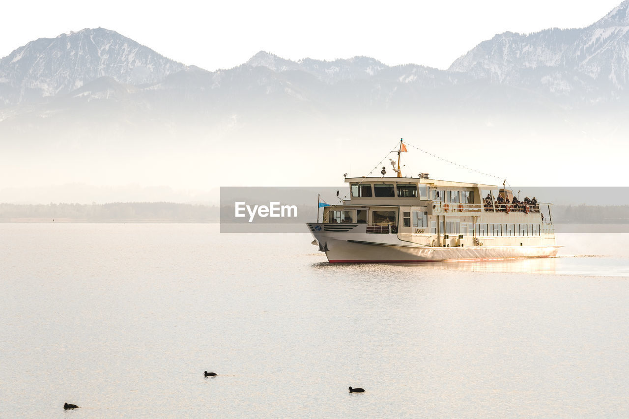 SHIP SAILING ON SEA AGAINST MOUNTAIN