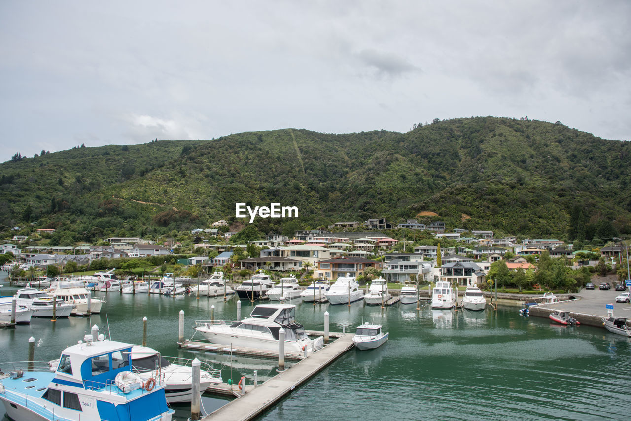 BOATS MOORED IN HARBOR AGAINST SKY