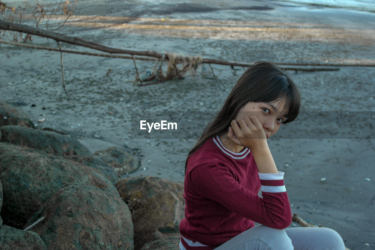 Portrait of girl sitting on rock by river