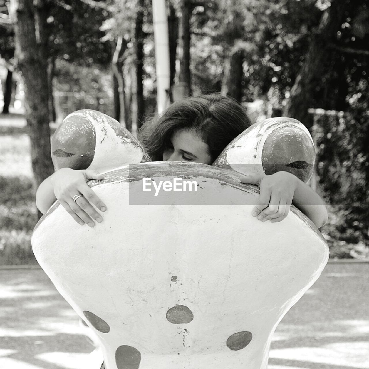 Woman embracing frog structure at park