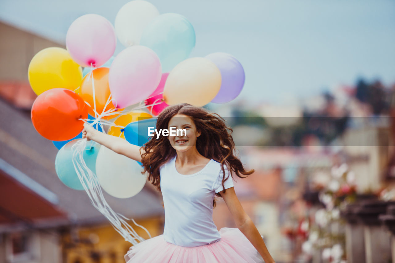 Smiling teenage girl holding balloons outdoors