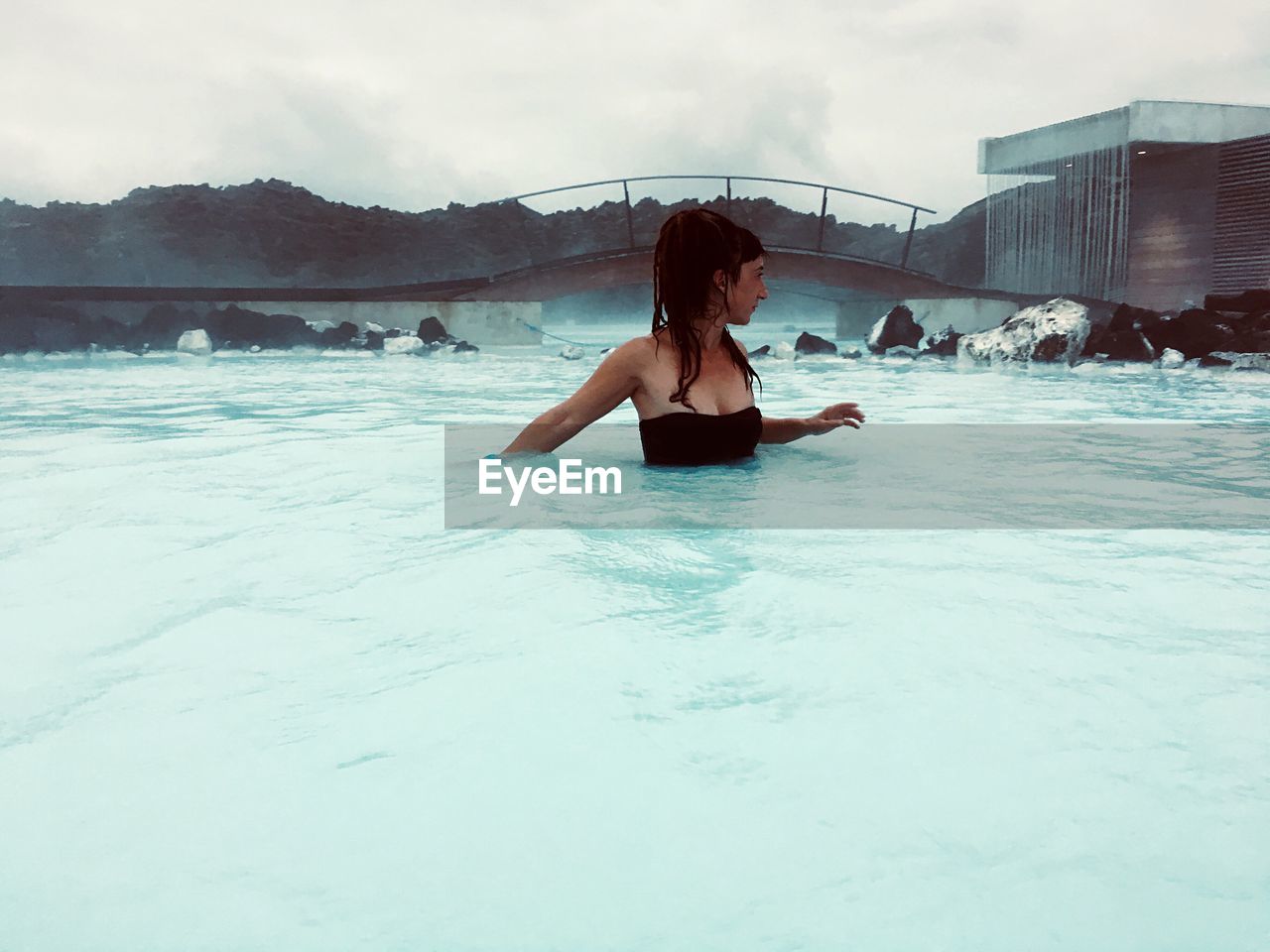 Woman in hot spring against sky