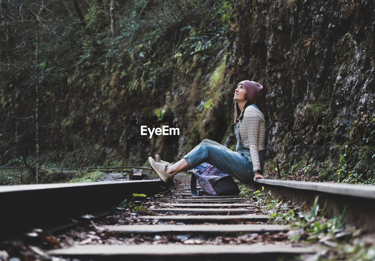 FULL LENGTH OF WOMAN SITTING ON RAILROAD TRACK