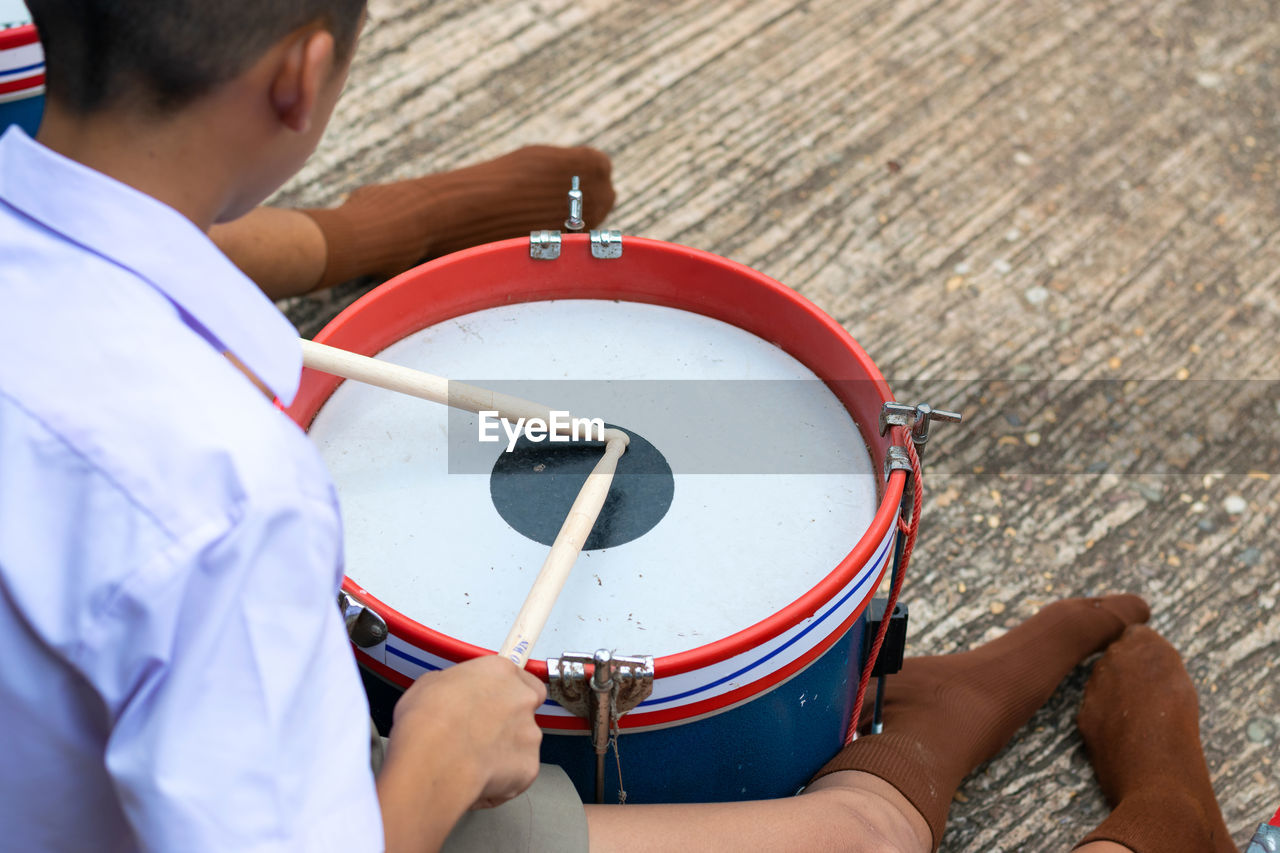 Man playing drum while sitting on floor