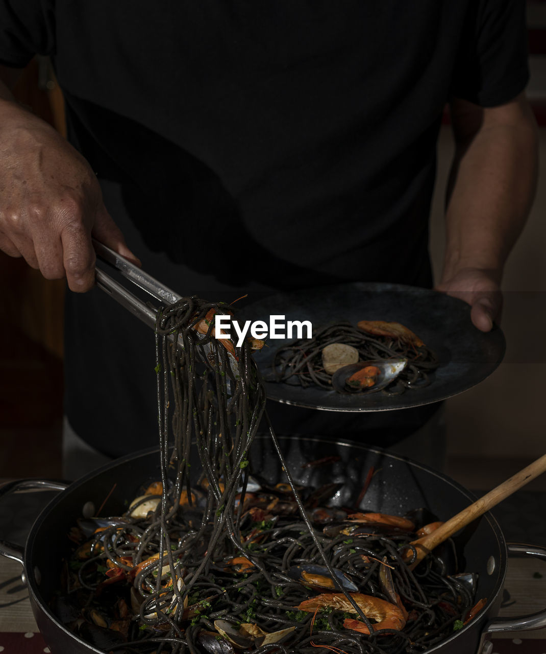 Man is serving black spaghetti.