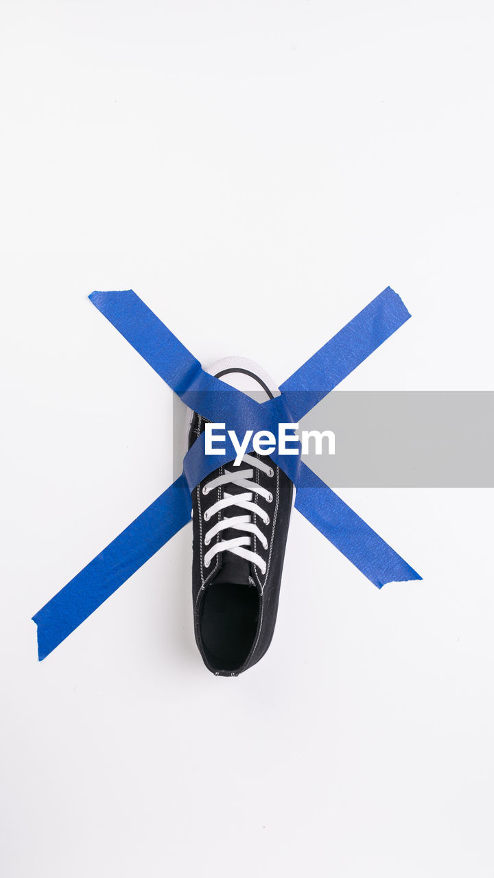 Directly above shot of canvas shoe and adhesive tape on white background