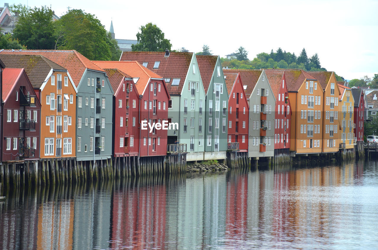 Buildings by river against sky