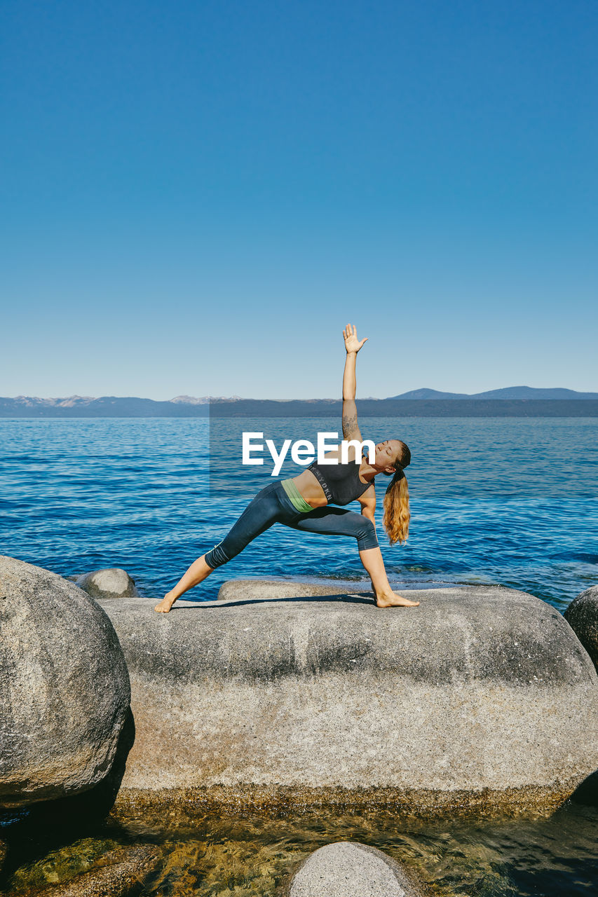 Young woman practicing yoga on lake tahoe in northern california.