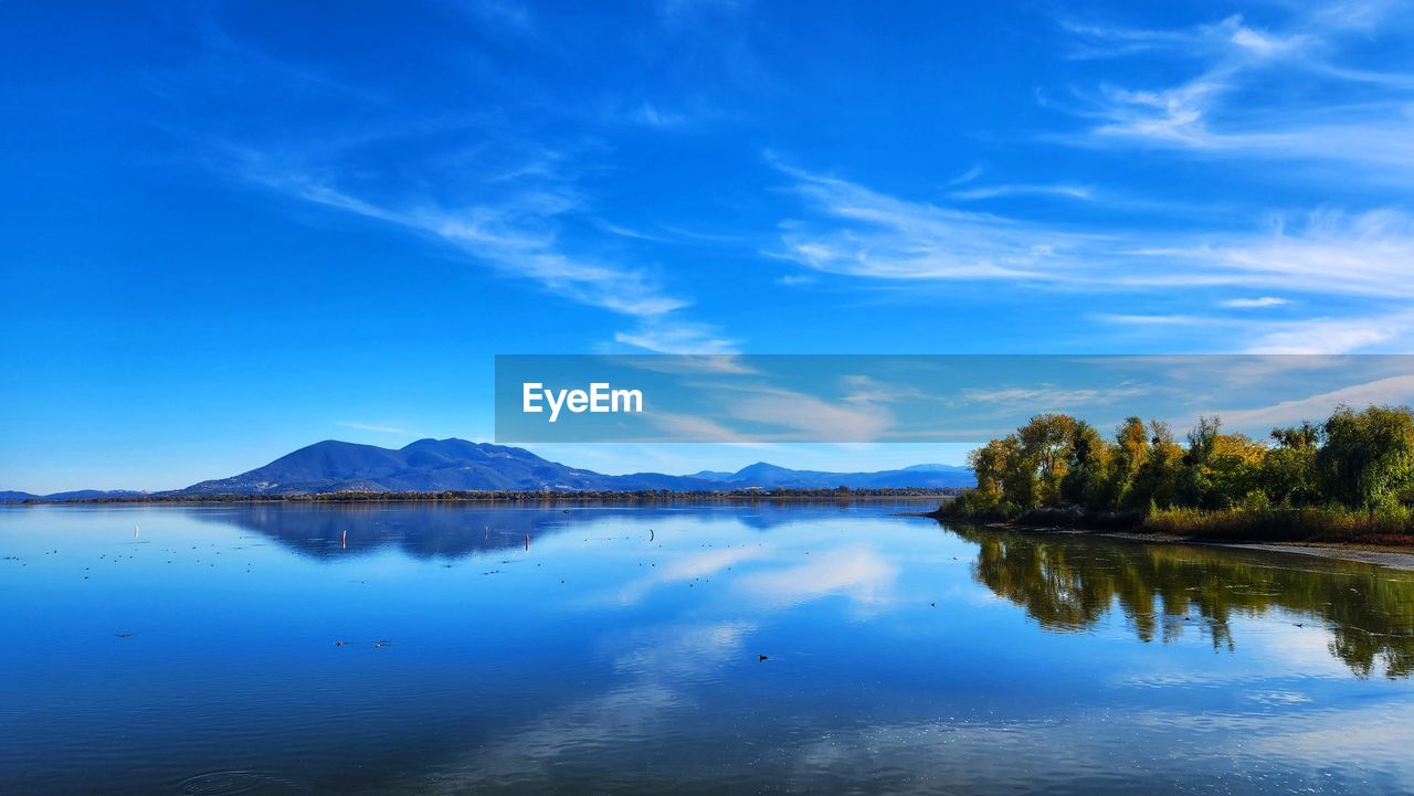 reflection, water, sky, scenics - nature, beauty in nature, lake, nature, tranquility, blue, mountain, landscape, tranquil scene, cloud, environment, dusk, tree, horizon, body of water, morning, no people, land, plant, travel destinations, sunlight, reservoir, outdoors, non-urban scene, travel, idyllic, shore, mountain range, day, forest, tourism