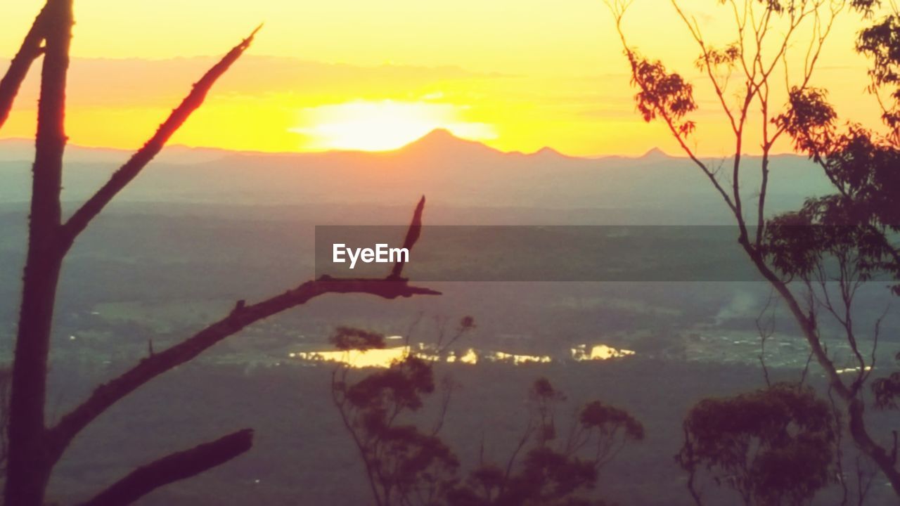 SCENIC VIEW OF SEA AND SILHOUETTE MOUNTAINS AGAINST SKY DURING SUNSET