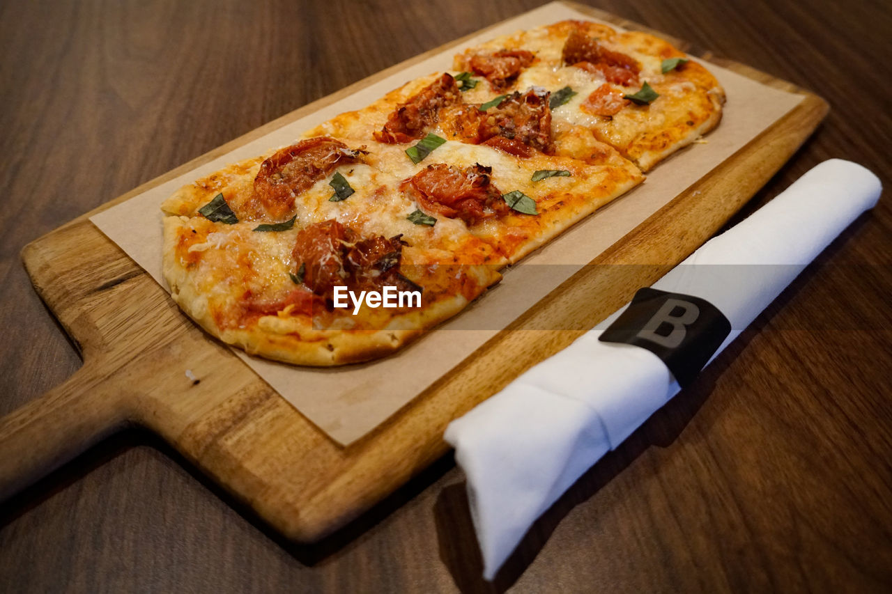 HIGH ANGLE VIEW OF PIZZA SERVED ON TABLE