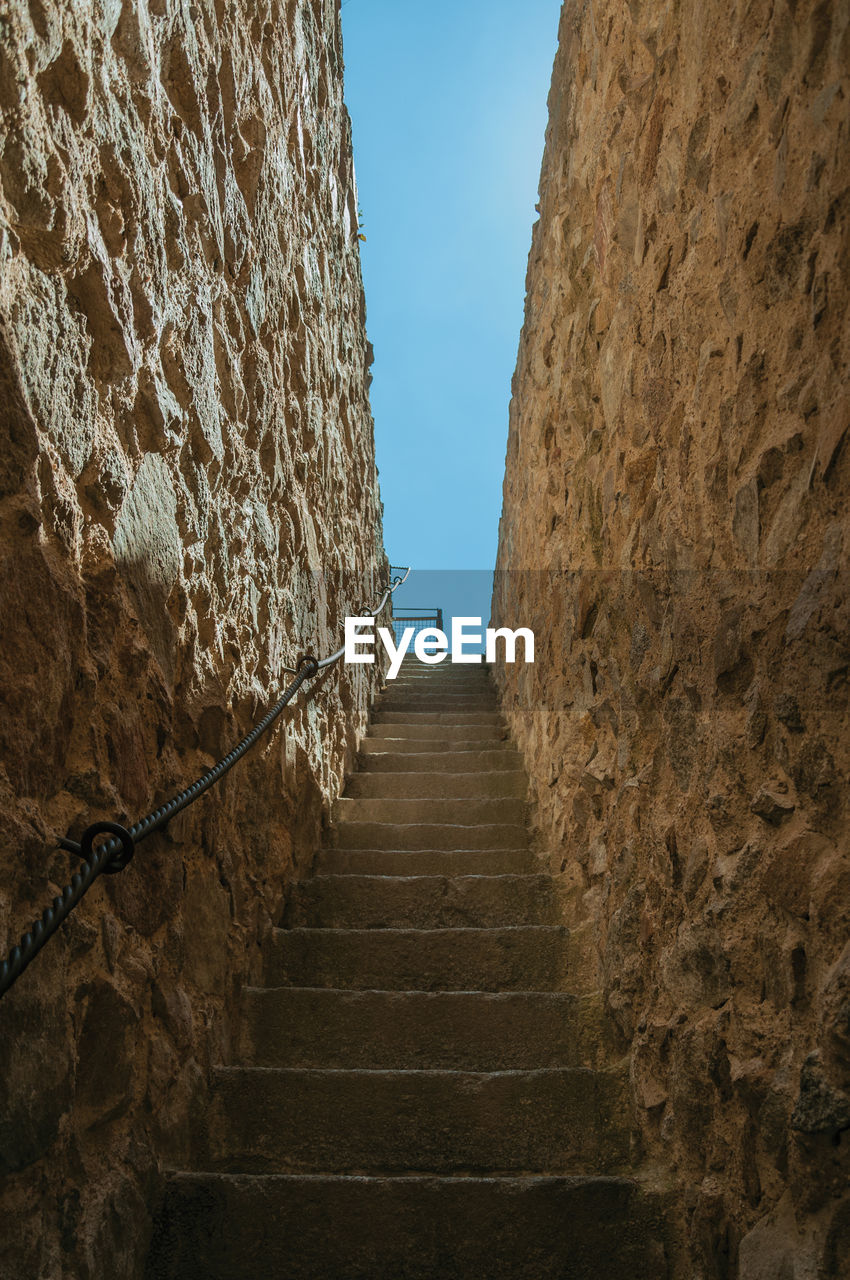 Staircase made of stone bricks going up towards a thick wall around the town in avila, spain.