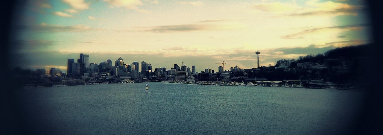 Panoramic shot of cityscape by sea against sky at dusk