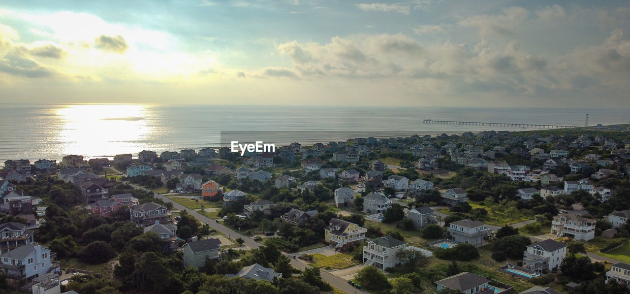 AERIAL VIEW OF SEA BY TOWNSCAPE AGAINST SKY