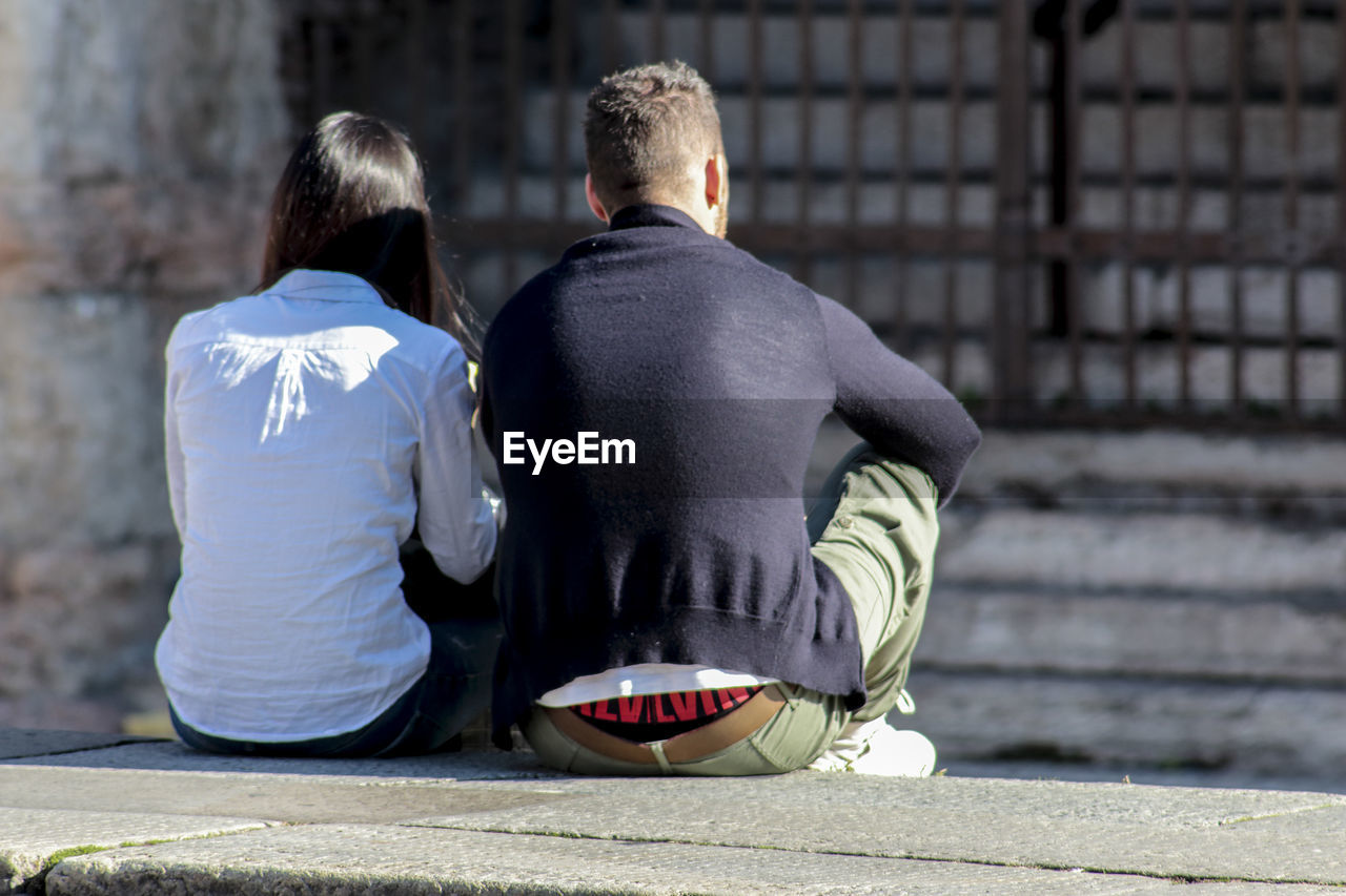 Rear view of couple sitting outdoors