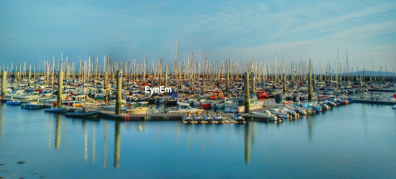 Sailboats moored at harbor against sky