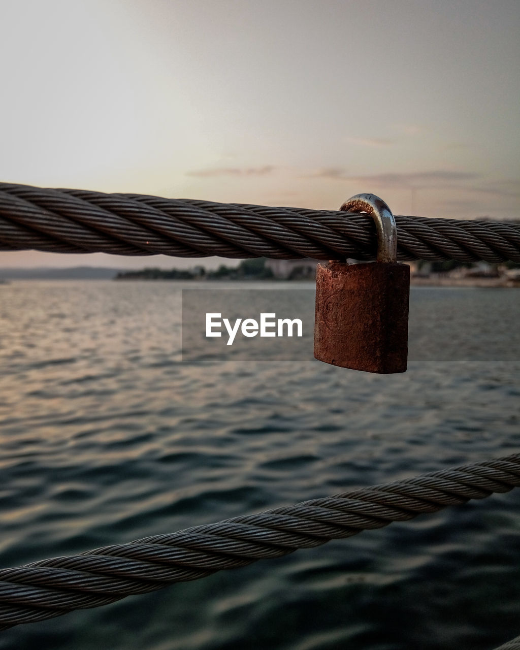 CLOSE-UP OF PADLOCKS ON RAILING AGAINST SKY