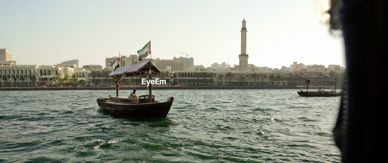 BOATS IN RIVER AGAINST BUILDINGS