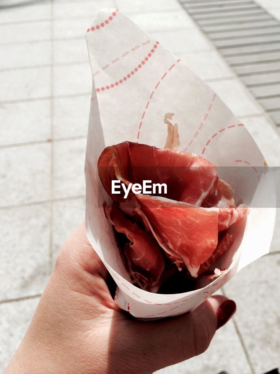 Cropped image of woman holding cone with sliced ham