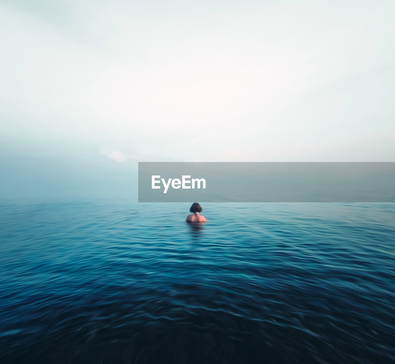 Man swimming in sea against sky