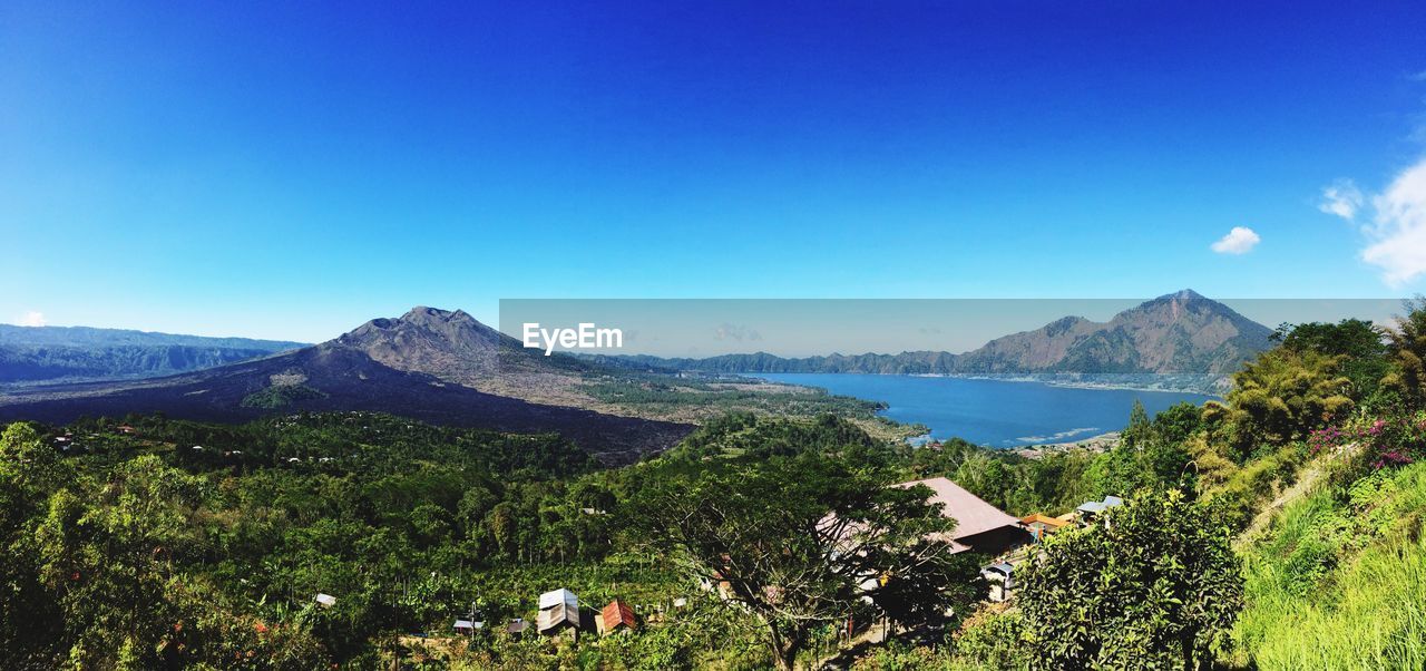 Scenic view of mountains and sea against clear blue sky