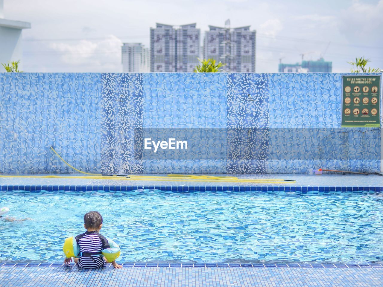 Rear view of boy swimming in pool