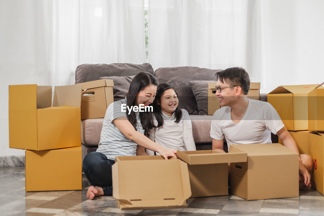 Smiling family packing cardboard while sitting at home