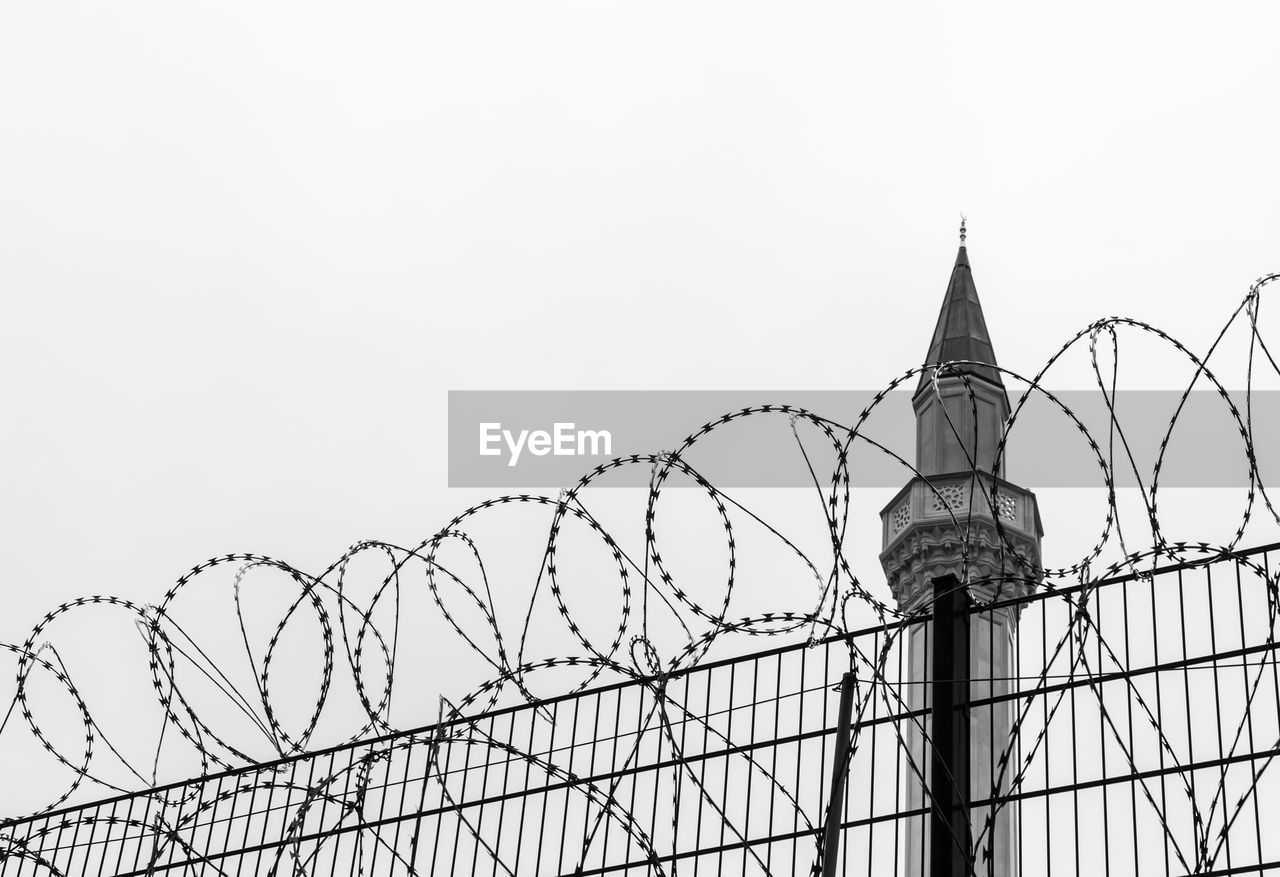 Low angle view of barbed wire against clear sky