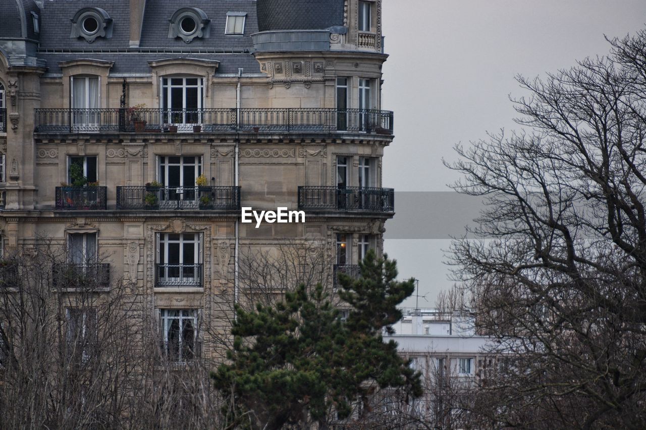 Building by trees against sky in city