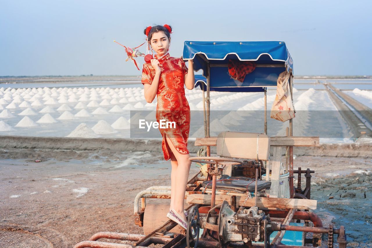 Beautiful women standing on car at beach against sky