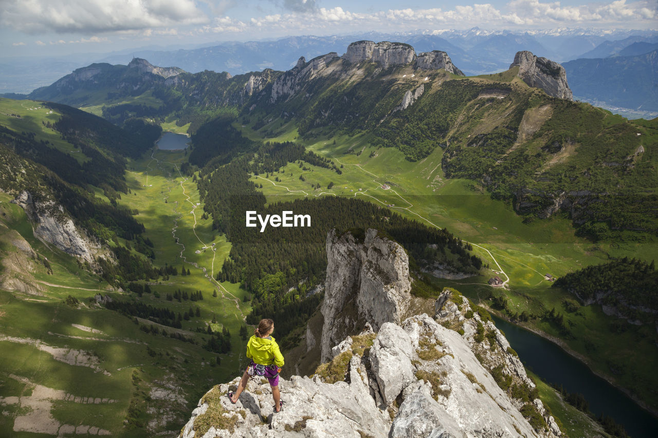 Rock climber on summit over valley, alpstein, appenzell, switzerland