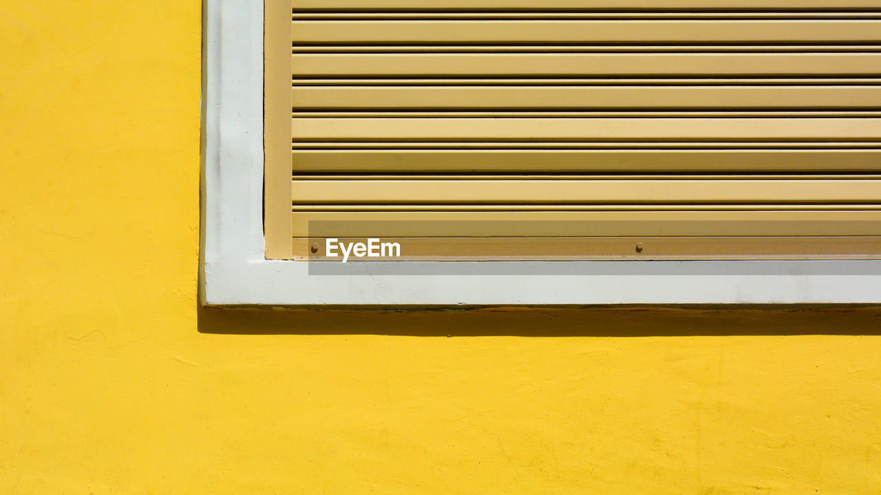 Close-up of window on yellow wall