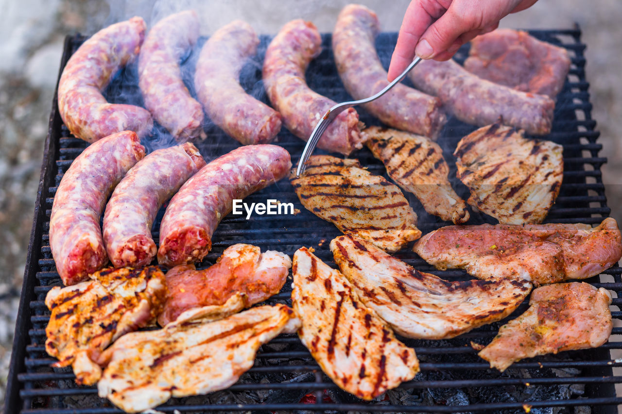 cropped hand of person preparing food on barbecue grill