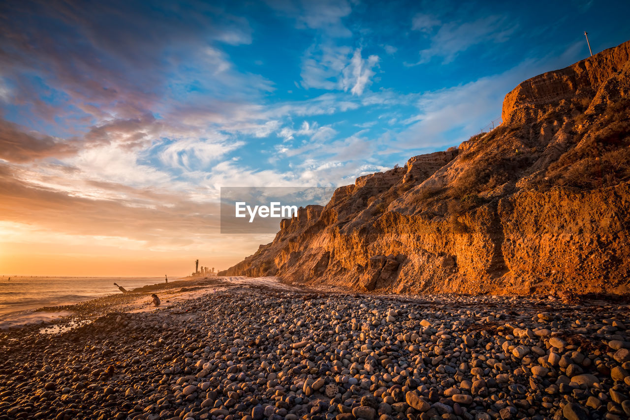 Beautiful beach sunset with sunlit bluffs and a rocky shore