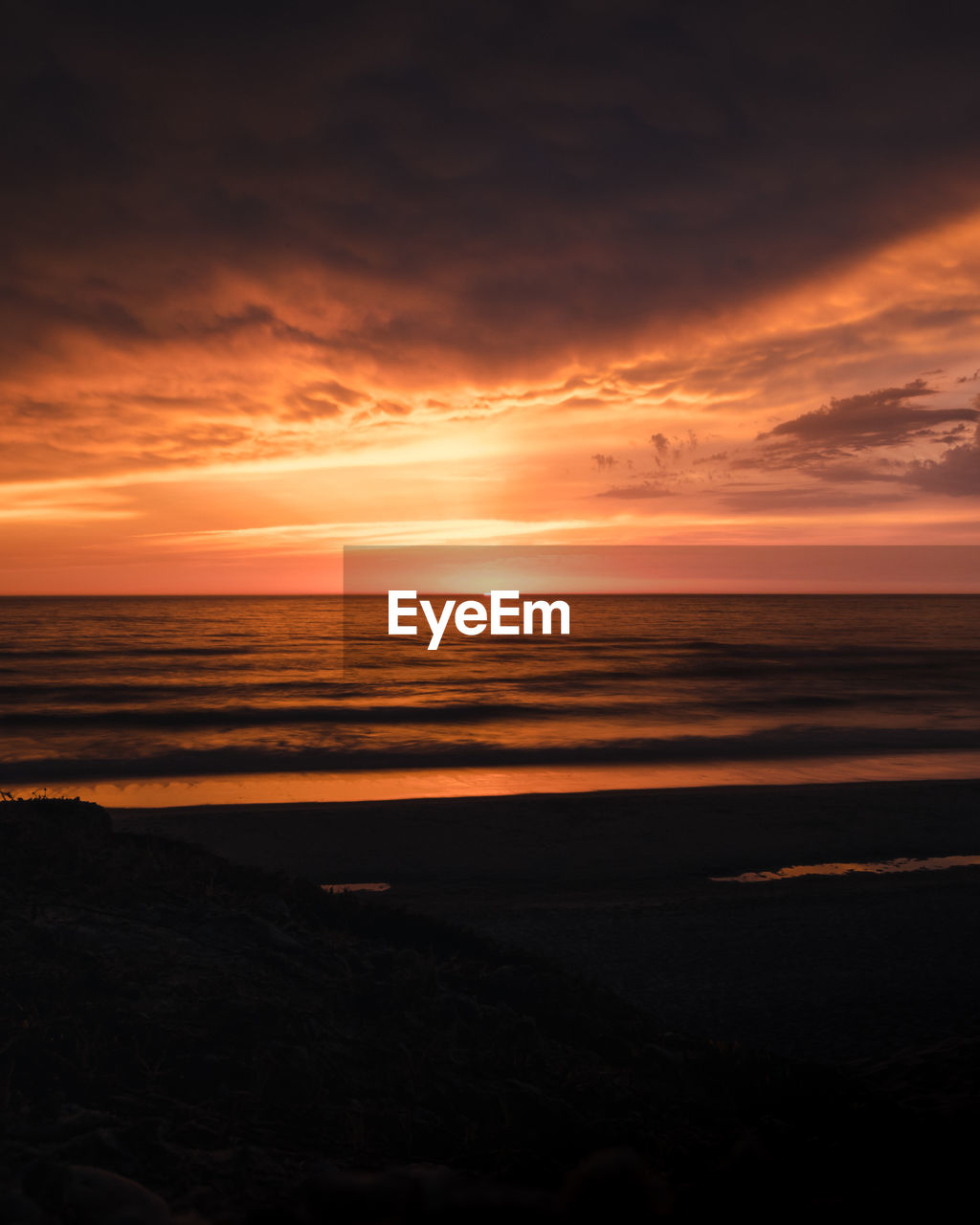 Scenic view of sea against dramatic sky during sunset