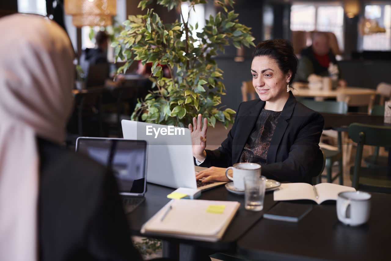 Smiling businesswoman using laptop in cafe