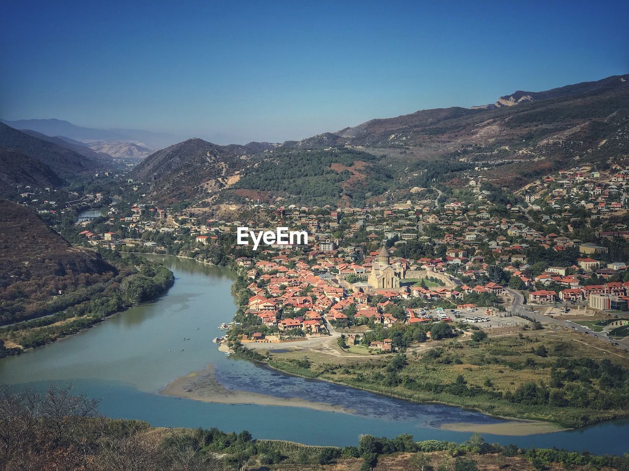 Aerial view of river by mountains against clear sky